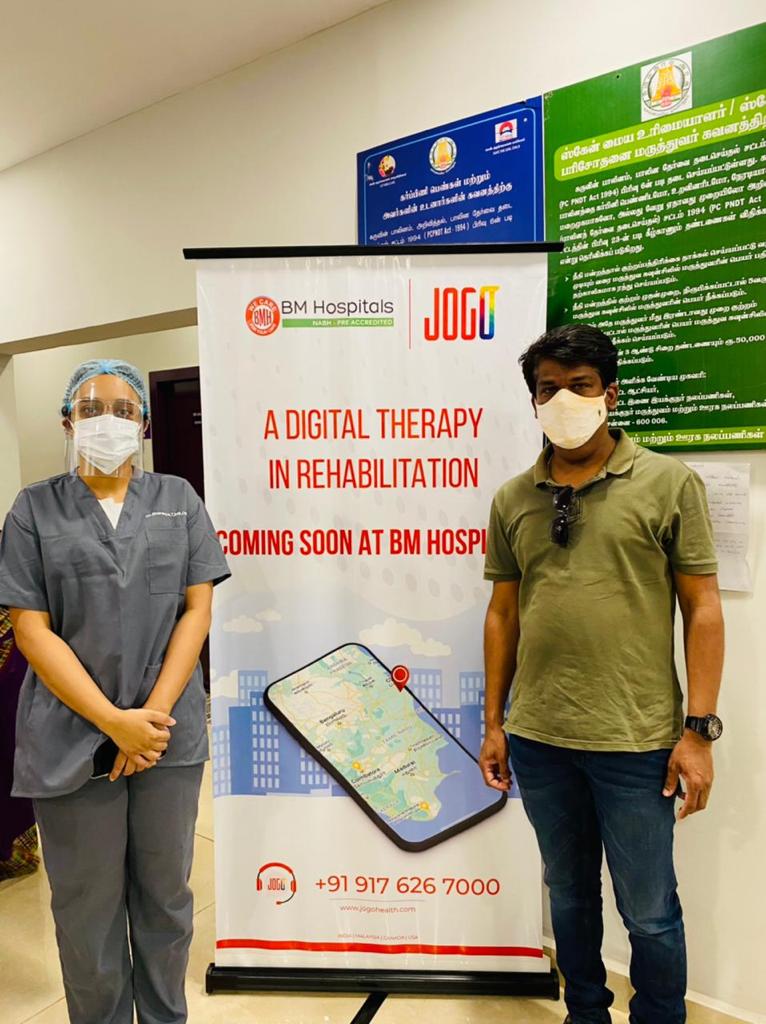 Image of a doctor and a client standing before a JOGO banner.