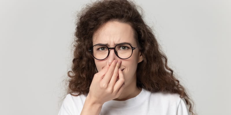 Curly-haired girl pinching her nose, indicating odor issues from incontinence.