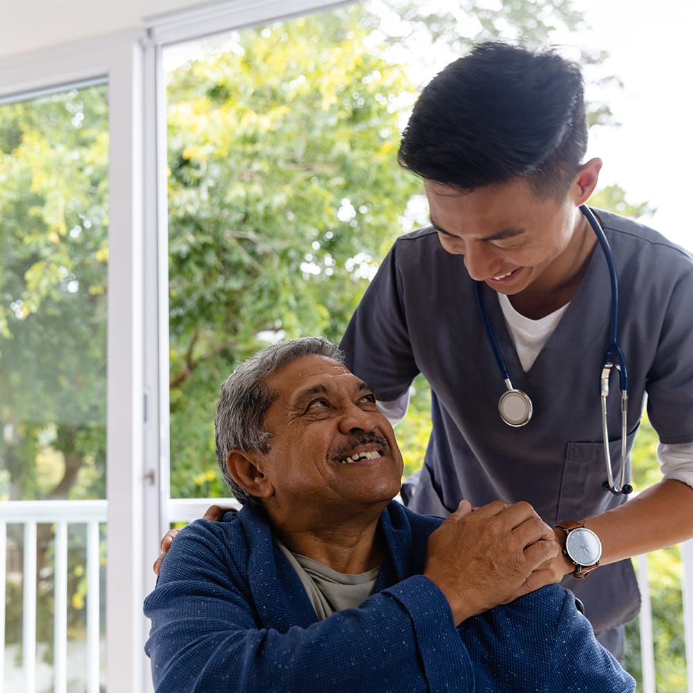 A candid shot of an elderly patient smiling warmly as he looks at a healthcare professional.